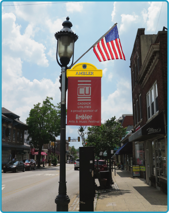 Lumen Banner with a bright yellow canopy displayed on a lamp pole in Ambler, PA.